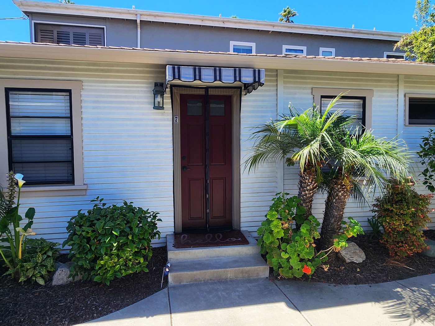 Cottage 7's front door under a striped awning, with palms behind