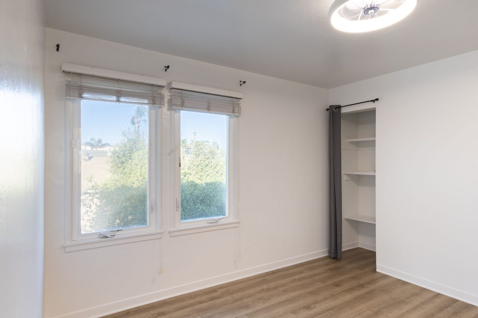 The bedroom in Apartment 1 with two windows and an open shelved closet