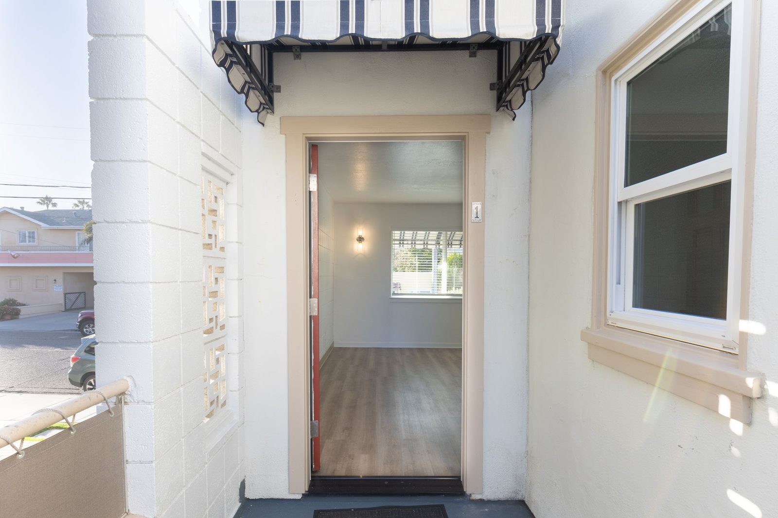 The front door of Apartment 1 under a striped awning, with a breeze-block screen wall beside it