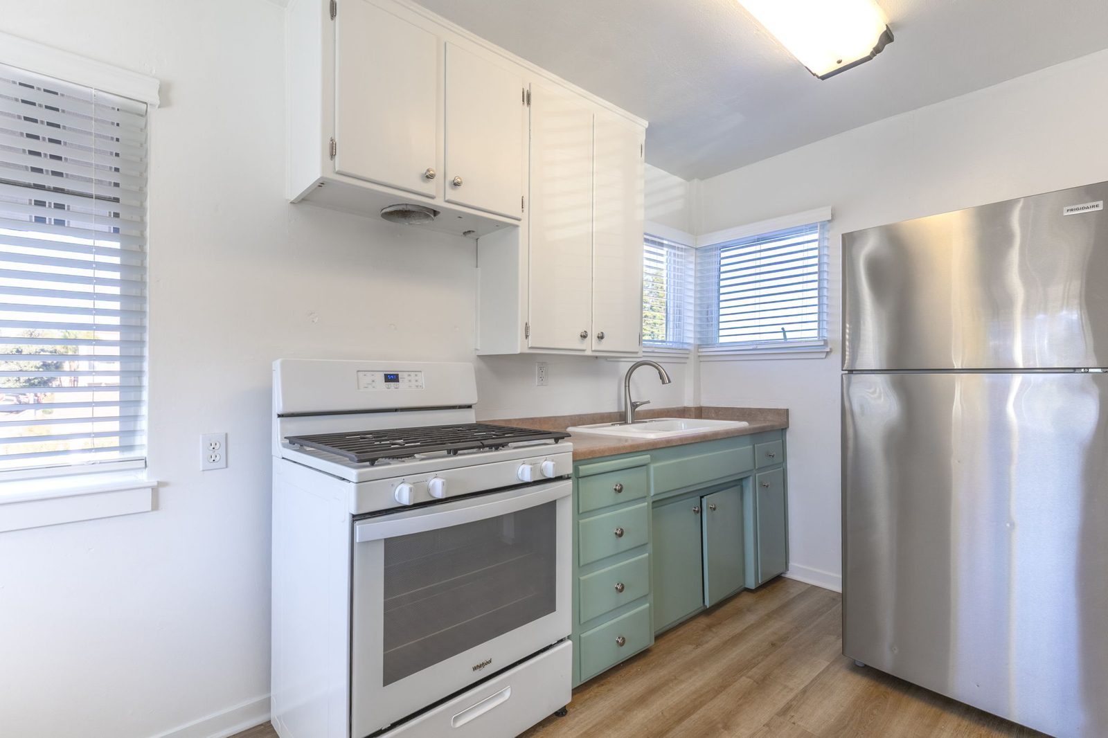 The kitchen in Apartment 1 with white upper cabinets, sea-green lowers and a gas range