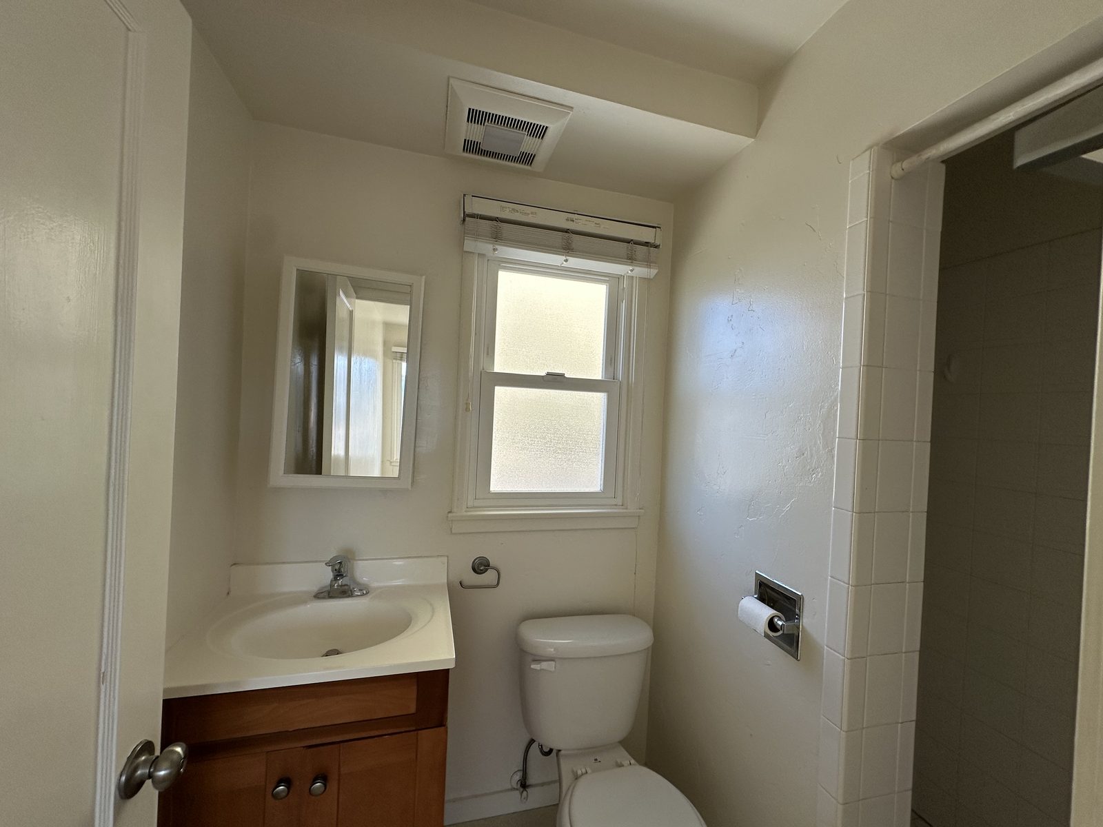 A bathroom in Apartment 2 with a tiled shower and a frosted window