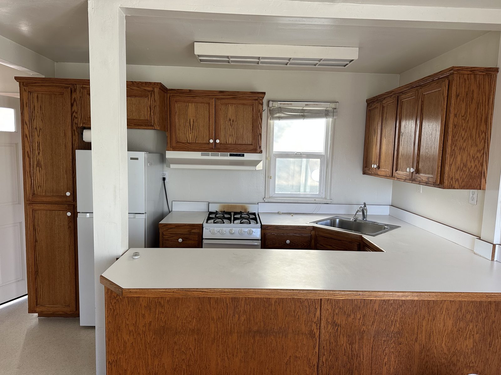 The kitchen in Apartment 2 with oak cabinets, a gas range and a wrap-around counter
