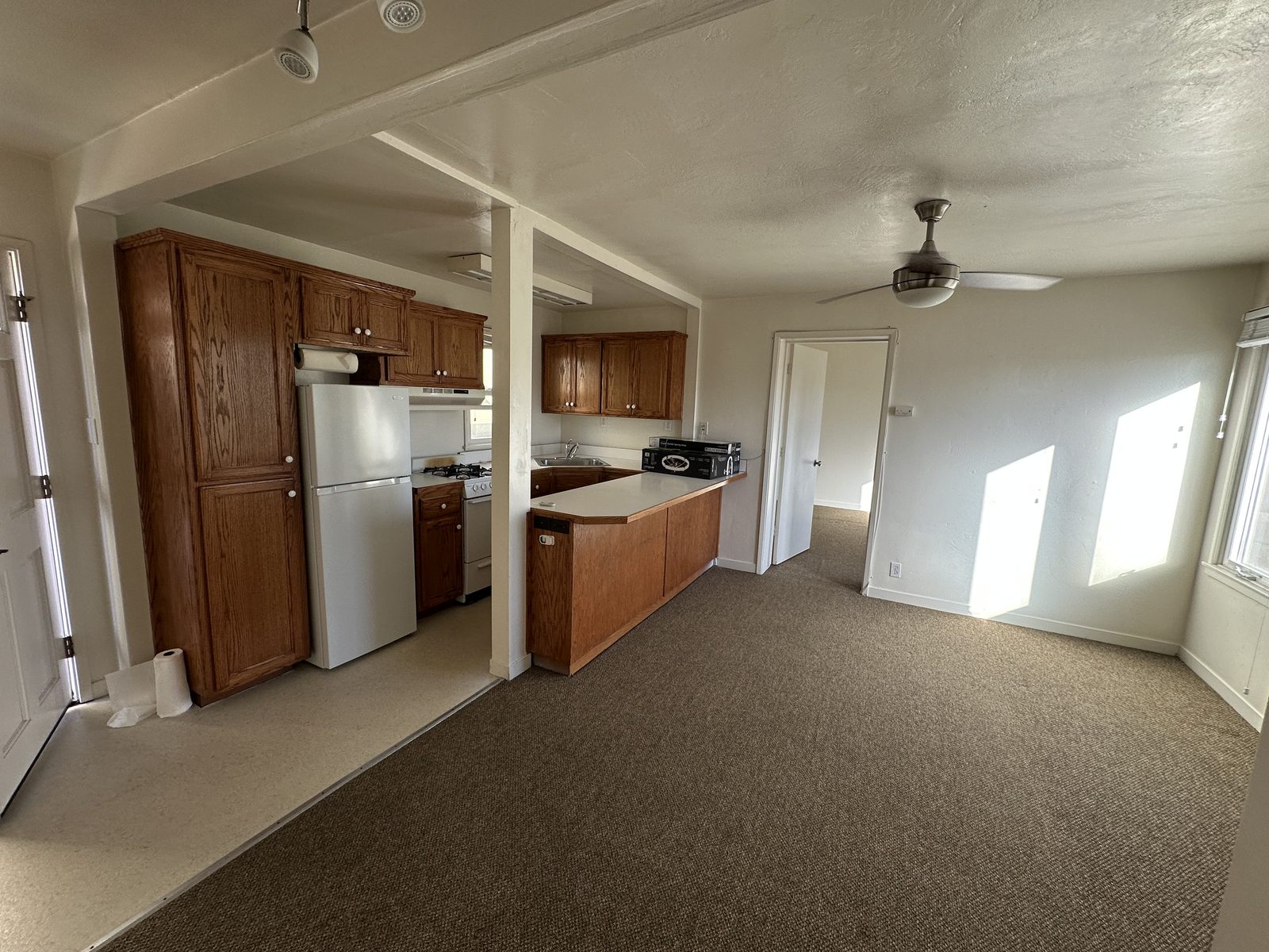 The living room in Apartment 2, open to the kitchen, with a ceiling fan and windows on the far wall